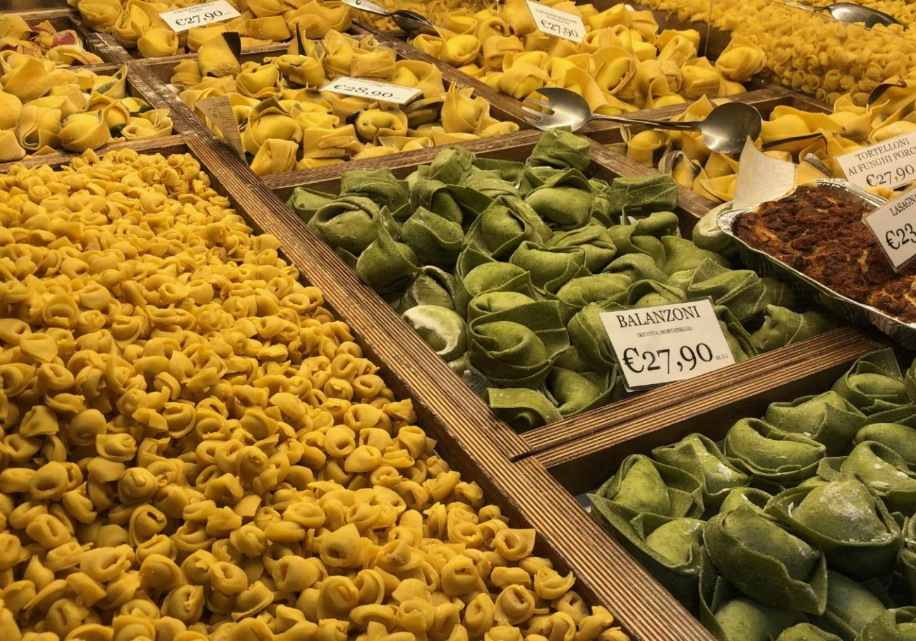 An Italian streetside market features various types of pasta and tortellini in Bologna 